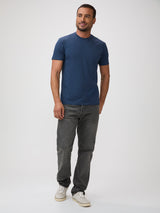 Man wearing a blue t-shirt and gray jeans on a white background