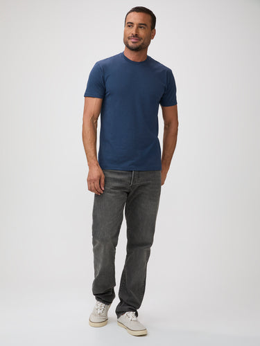 Man wearing a blue t-shirt and gray jeans on a white background