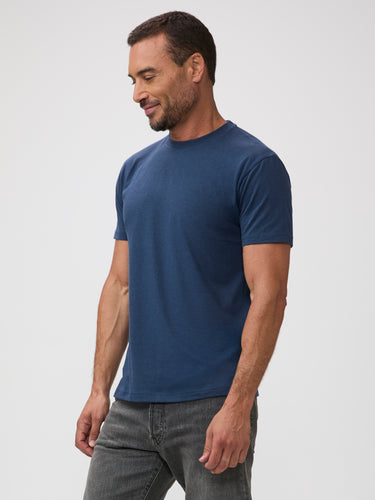 Man wearing a blue t-shirt and gray jeans on a white background