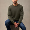 A man wearing an army green waffle flannel and blue jeans, sitting. A better thermal for a great price.
