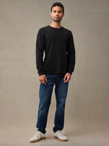 A man wearing a black long-sleeve flannel shirt, dark blue jeans, and white sneakers. 280 GSM waffle knit traps warmth without overheating