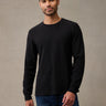 A man wearing a black long-sleeve flannel shirt and blue jeans. The thermal that keeps up with the whole weekend.