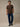 A man wearing a brown short-sleeve crewneck t-shirt, dark blue jeans, and black shoes. The tee that holds up to the whole weekend's to-do list.