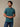 man wearing a teal short-sleeve crewneck t-shirt and blue jeans