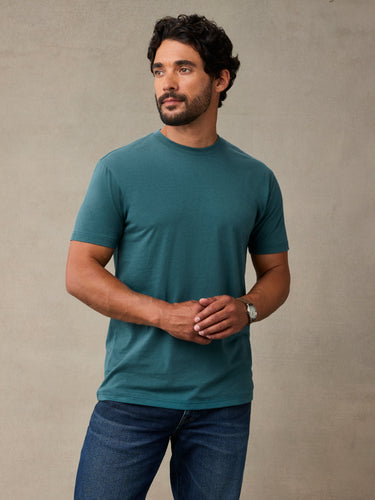 man wearing a teal short-sleeve crewneck t-shirt and blue jeans