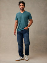 Man in teal v-neck t-shirt standing, casual style. Teal blue v-neck t-shirts for everyday wear.