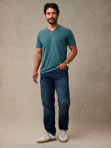 Man in teal v-neck t-shirt standing, casual style. Teal blue v-neck t-shirts for everyday wear.