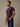 man wearing a deep mulberry colored short-sleeve crewneck t-shirt and blue jeans, standing 